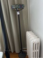 Full view of the floor lamp showing stained glass shade, twisted metal column, and decorative base