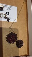 View of garnet necklace pendant, ring, earrings and brooch on auction tag