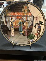 Front side of the collector's plate showing detailed scene of Dressing the Empress with decorative border.