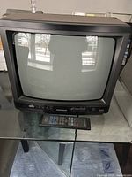Magnavox 14-inch CRT tube television shown on a glass table with remote control placed in front.