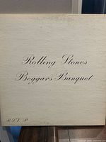Front cover of Beggars Banquet vinyl album showing title and band name in cursive on a white background.