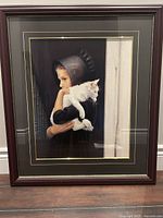 Photo of framed wall art "Sarah" depicting a young girl holding a white cat, framed in dark wood with double matte