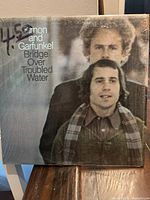 Front cover of the vinyl album showing Simon and Garfunkel with text 'Bridge Over Troubled Water'.