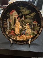 Front of the decorative plate with painted scene of Elena the Fair and man in classical garden, with detailed architectural and natural elements