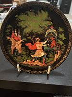 Front of the plate showing a painted scene with a man in traditional dress, a golden cage, tree, and background buildings with intricate gold border.