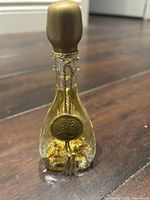 Clear tear-drop shaped glass perfume bottle with gold embossed label and gold stopper