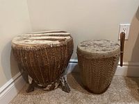 Both African animal skin drums positioned side by side, showing size difference, materials, and weaving detail.