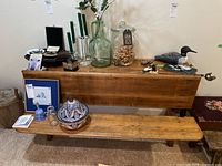 Full view of the antique wood school bench with the desk top behind it, various decorative objects placed on top.