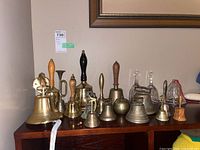 Full lot view on wooden surface showing brass, glass and wooden handle bells