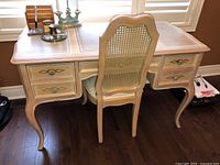 Front view of whitewashed wood desk and matching cane-back chair