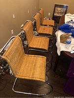 Four armless chairs and two armchairs lined up on floor showing overall set