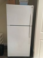 Front view of white GE top freezer refrigerator, closed.