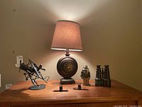 Full lot showing lamp, airplane sculpture, pilot figurine, binoculars, and smaller plane sculptures on wooden surface.