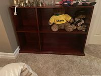 Full view of the shelving unit showing all four open shelves with some content on the top shelf and surface.