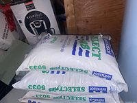 Three large white bags of Windsor Select Plus water conditioner salt, stacked horizontally, showing brand and product details.