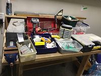 Photo of two metal tool carrying cases on a workbench, showing assorted tools and hardware including hand tools, tapes and small containers.