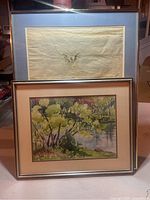 Two framed watercolours leaning against stairwell showing both artworks in same scene.