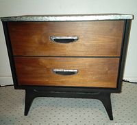 Front view showing walnut drawer fronts, black painted sides and legs with silver leaf details on handles and trim