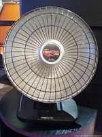 Front view of the Presto HeatDish Plus heater showing the large parabolic element with protective grill and logo.