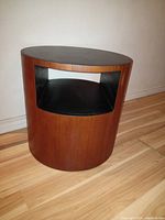 Full view of round teak drum table showing open interior shelf