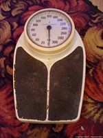 Top view of vintage Health O Meter scale showing dial and footpads, placed on a patterned carpet.