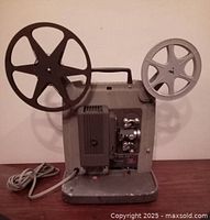 Front view of vintage Keystone Ninety 8mm film projector showing reels mounted and power cord.