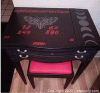 Top view of sewing machine table showing Ouija board design with red lettering and moth graphic, plus moon phase pattern on side.