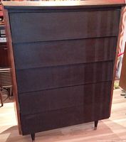 Front view showing five drawers with matte black fronts and walnut side panels