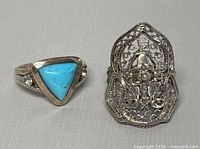 Two vintage rings: one with a turquoise triangular stone and small side stones, another with intricate filigree design in silver.