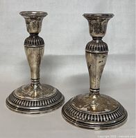 Front view of both candleholders showing overall shape, design, and wear
