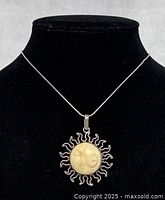 Necklace displayed on black mannequin showing the sun pendant with hand carved face design.