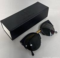 Sunglasses positioned with ATTCL eyeglasses case closed beside them, showing overall condition and items included.