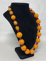 Necklace displayed on black velvet bust, showing full 26-inch strand of graduated butterscotch beads with amber spacers