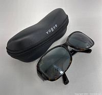 Maui Jim sunglasses with Vogue eyeglasses case shown together, case is black with logo printed.
