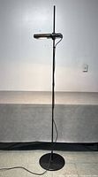 Full view of the adjustable black Artemide floor lamp standing on a circular base