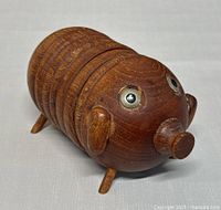 Pig shaped teak wooden coasters assembled as a pig figurine showing pig head with metal eyes, snout, ears and legs.