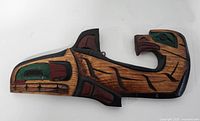 Front view of carved whale wooden wall plaque with Haida style painted decoration.