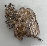 Close-up top view showing the detailed filigree flowers and leaves of the silver brooch