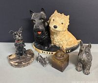 Full view of six Scottie dog figurines including the Black & White Scotch Whiskey bar display and varied smaller figurines arranged in front and on sides.