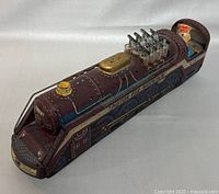 Front and side view of the vintage tin toy train showing piston details and sailor figure driver in the cab.