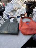 Two leather purses side by side on a gray surface, showing shape and texture details.