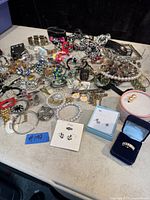 Full view of assorted jewelry including bracelets, earrings, rings, necklaces, and brooches spread on table.