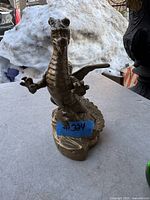 Front angle view of the solid brass dragon figurine placed on a table with snow in the background.
