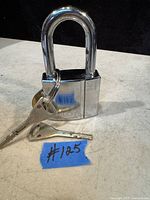 Padlock standing on a surface with two keys attached to its shackle shown in clear detail.