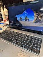Acer Aspire laptop powered on showing Windows lock screen with desktop wallpaper