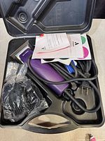 Open view of the hair clipper kit showing the clipper, assortment of attachment combs, instruction booklets, power cord, and carrying case interior.