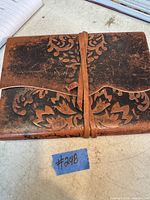 Closed view of leather journal showing embossed floral pattern and leather strap closure.