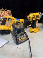 Photo of DEWALT sawzall, drill, battery and charger on table showing wear and condition.