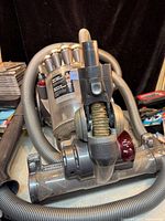 Dyson vacuum cleaner power head with hose attached, showing wear and use marks.