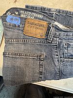 Folded vintage Levi's Signature blue jeans showing leather branding patch and relaxed straight label